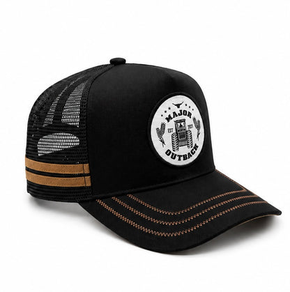 A black trucker hat with a white circular 'Major Outback' patch on the front, black mesh back panels, and tan contrast stitching on the brim and side.